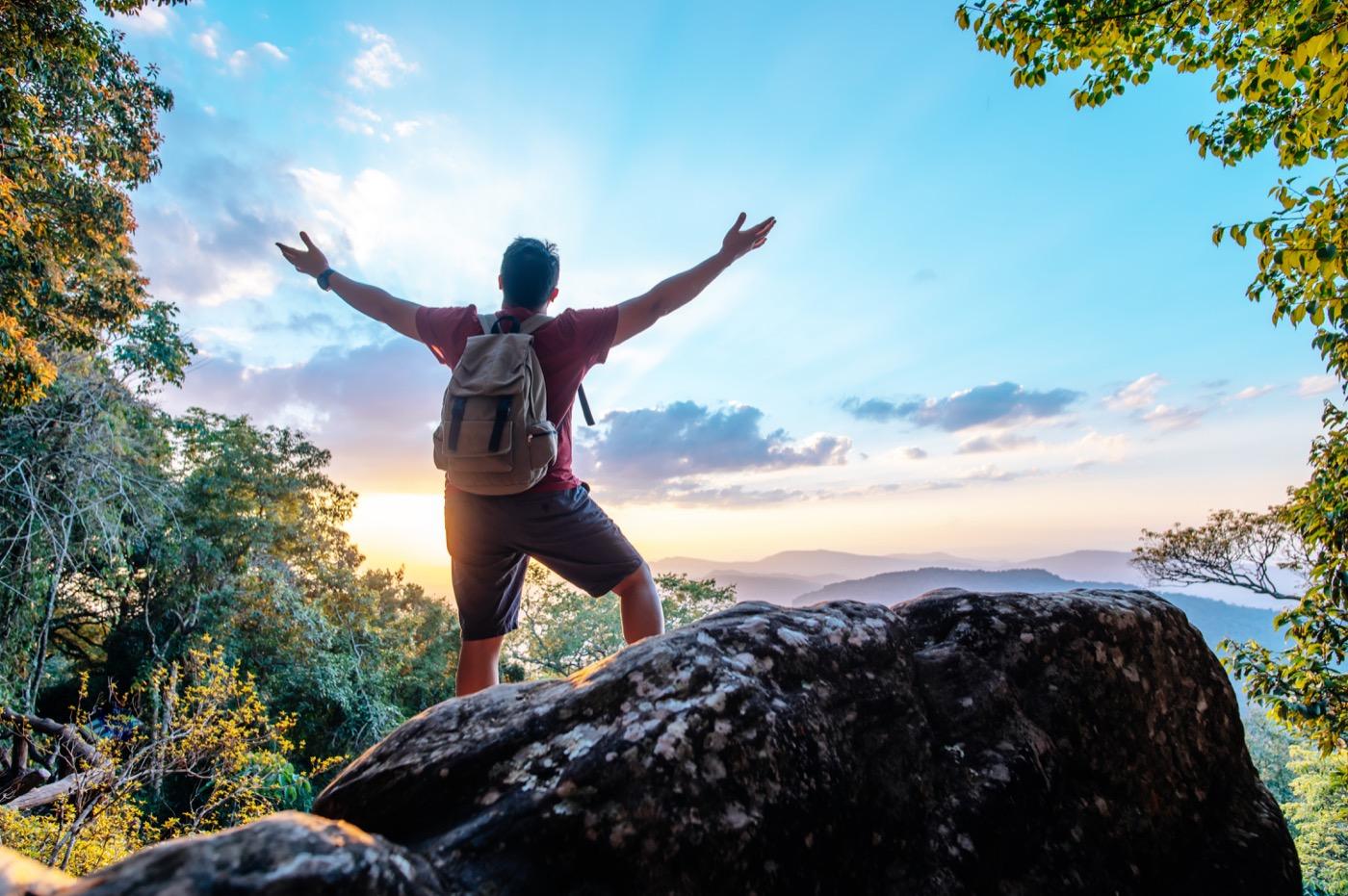 Hiker with arms raised on a mountain peak at sunrise